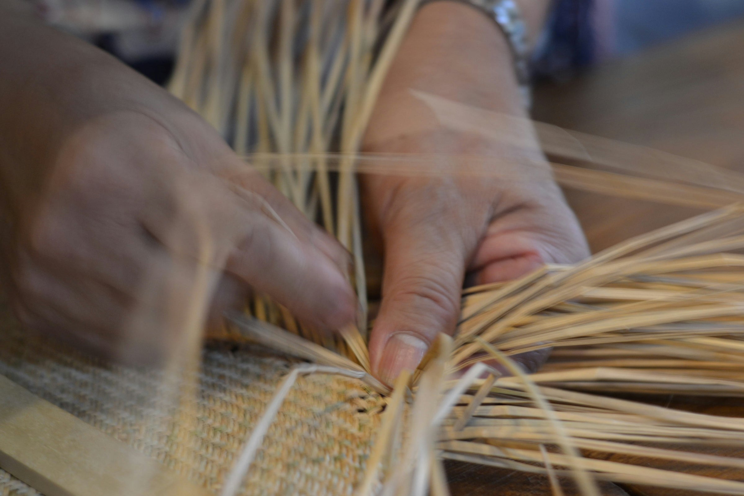 Close-up of hands working with woven natural fibres